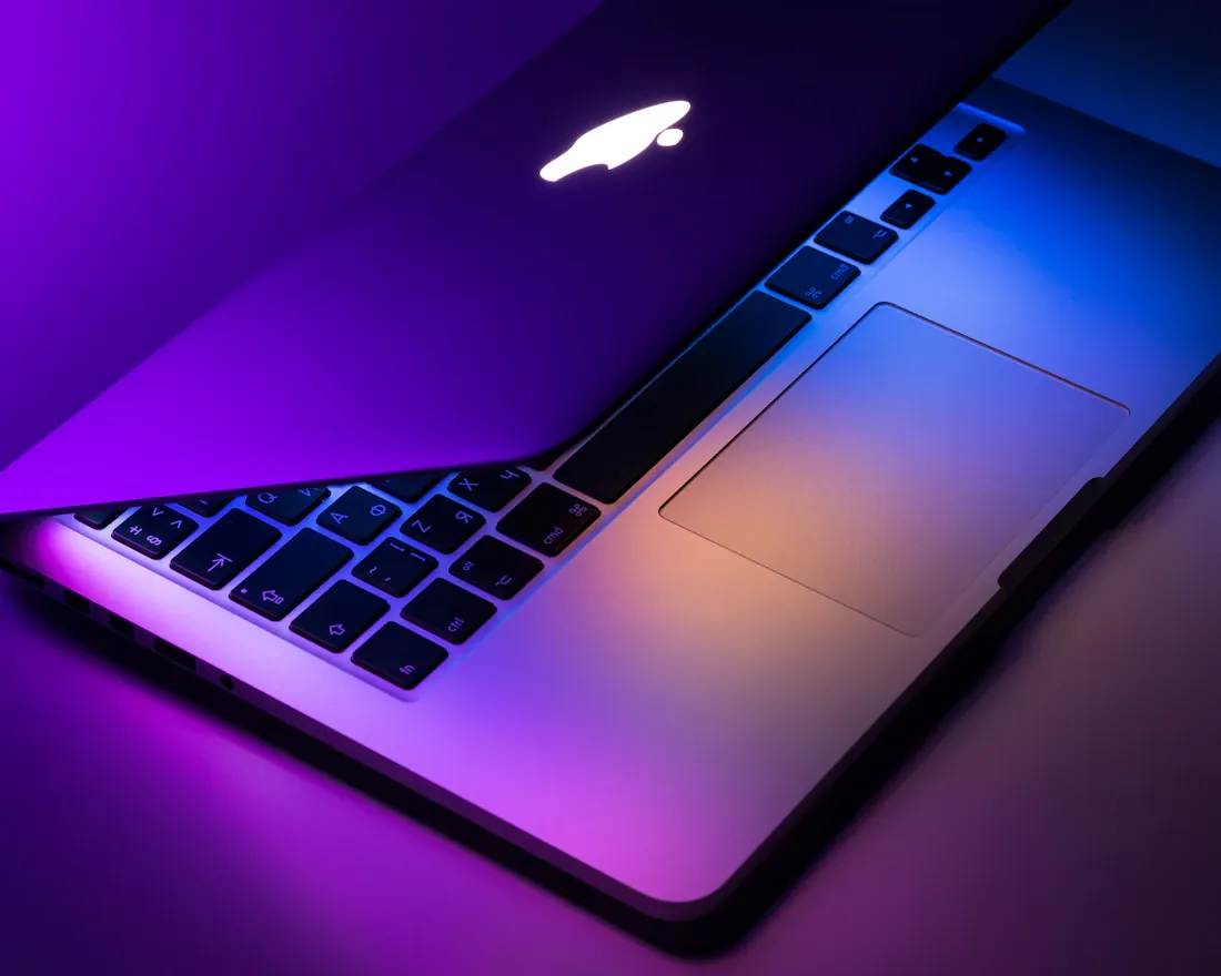 Close view of a laptop illuminated by purple and blue light