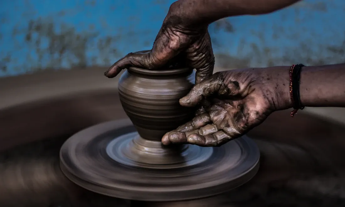 Hands carefully shaping clay on a pottery wheel