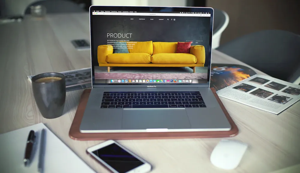 Laptop displaying a product landing page beside design materials